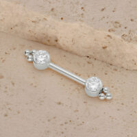 Barbell en or blanc pour téton avec zirconia Barbell en titane blanc avec deux zirconias sur fond sablonneux