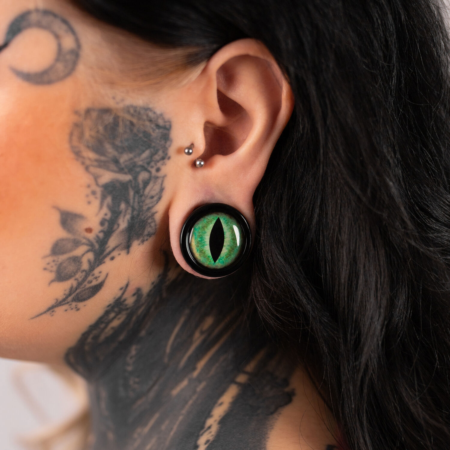 Verena Venus Plug avec œil de chat vert Grand plug œil de chat vert dans l'oreille d'une personne tatouée