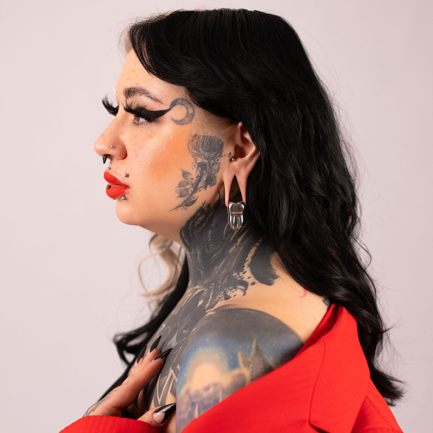 Verena Venus poids d'oreille en noir et argent Femme avec des tatouages portant un poids d'oreille noir et argent, vêtement rouge