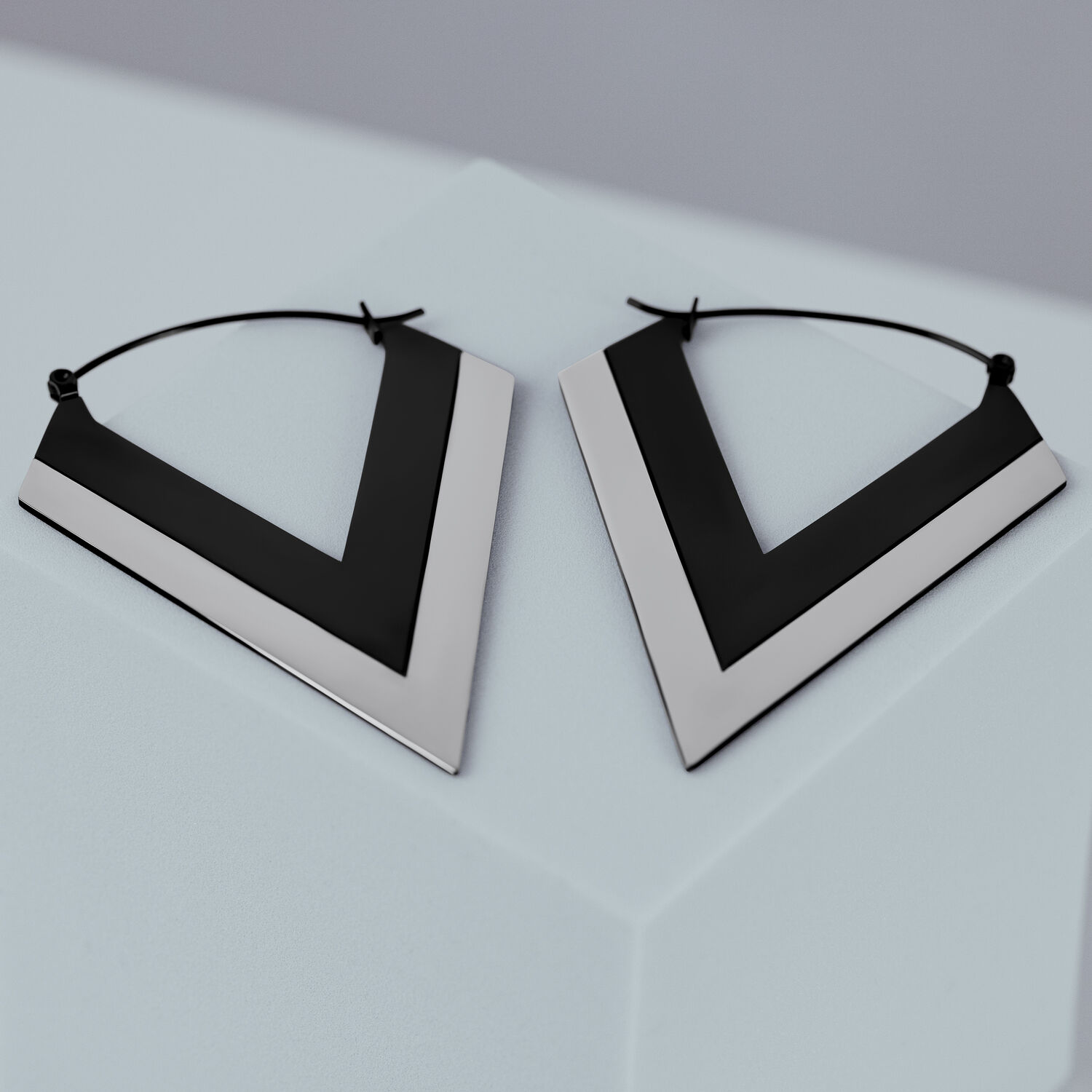 Boucles d'oreilles en forme de V argentées et noires sur fond gris