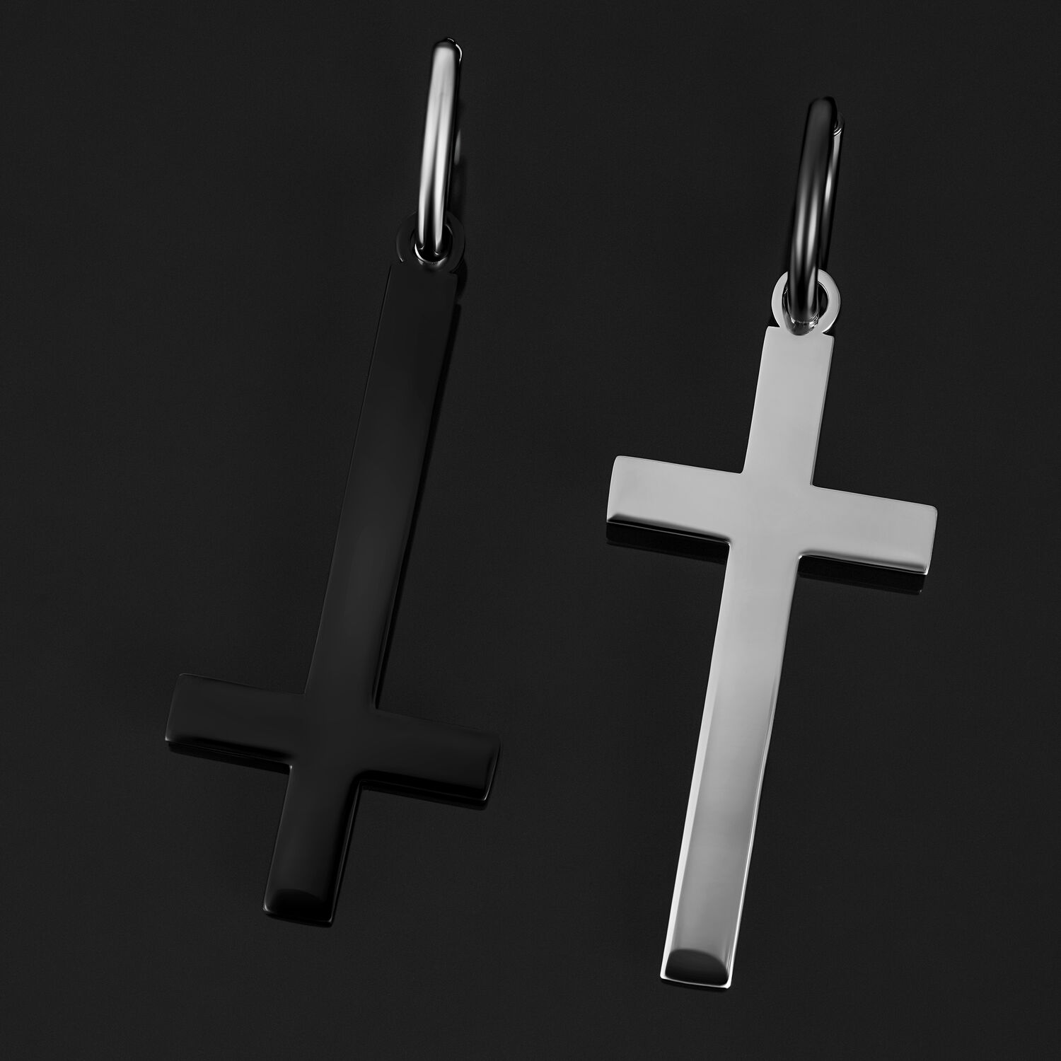 Deux boucles d'oreilles en forme de croix, l'une en noir brillant, l'autre en argent, sur fond noir