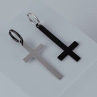 Deux boucles d'oreilles croix en acier chirurgical or et noir sur fond gris