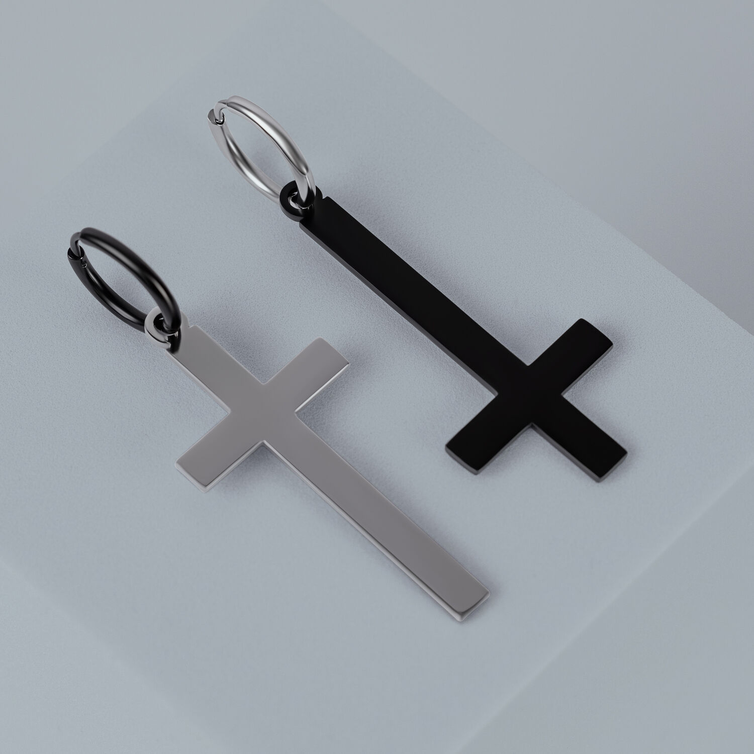 Deux boucles d'oreilles croix en acier chirurgical or et noir sur fond gris