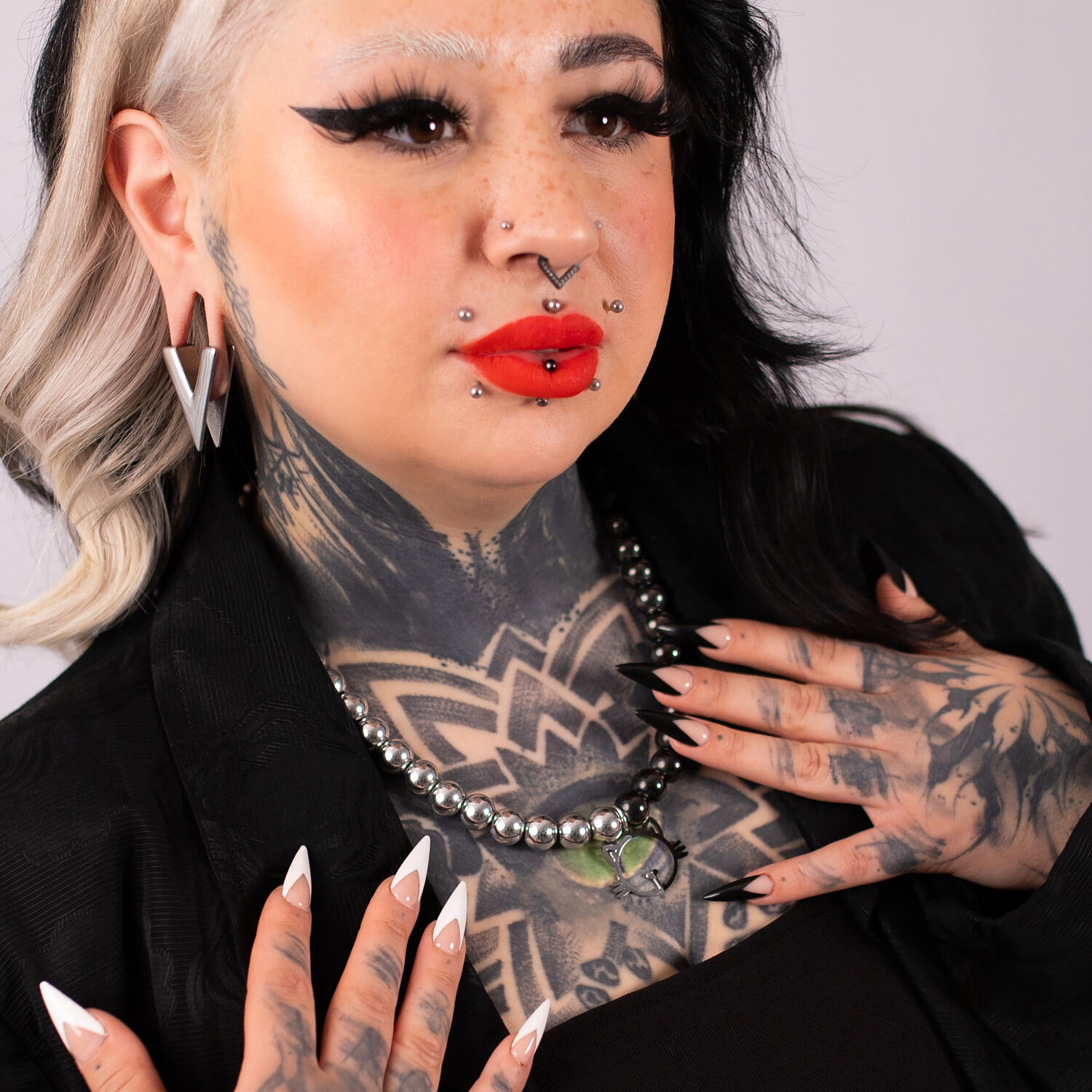 Collier Bulles de Chat Noir et Argent de Verena Femme tatouée portant un collier Bulles de Chat Noir et Argent avec piercings, fond noir