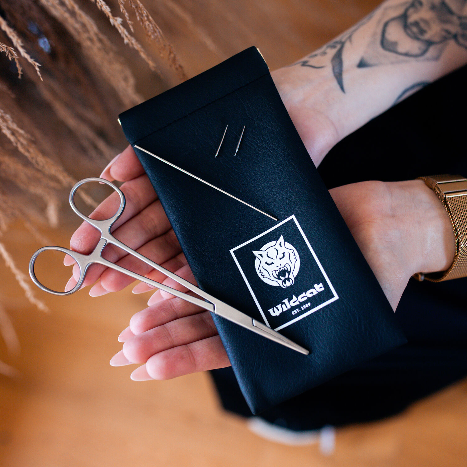 Kit de changement de piercing avec ciseaux et aiguille Étui noir avec logo Wildcat, deux aiguilles et ciseaux, tenu dans les mains