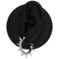 Boucles d'oreilles en argent à pointes sur un modèle d'oreille noir sur fond blanc