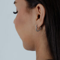 Boucles d'oreilles Heart Bubble Hoops argentées Femme de profil portant des boucles d'oreilles cœur argentées sur fond gris