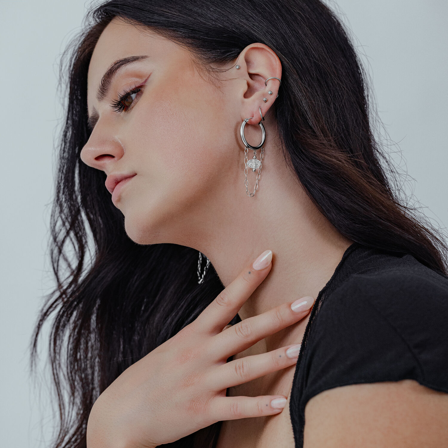 Edgy boucles d'oreilles blanches en pierre à l'oreille Femme aux longs cheveux noirs portant des boucles d'oreilles blanches en pierre en acier chirurgical à l'oreille