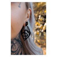 Boucles d'oreilles Snake Hoops noires en acier Gros plan d'une oreille avec des boucles d'oreilles Snake Hoops noires, arrière-plan flou