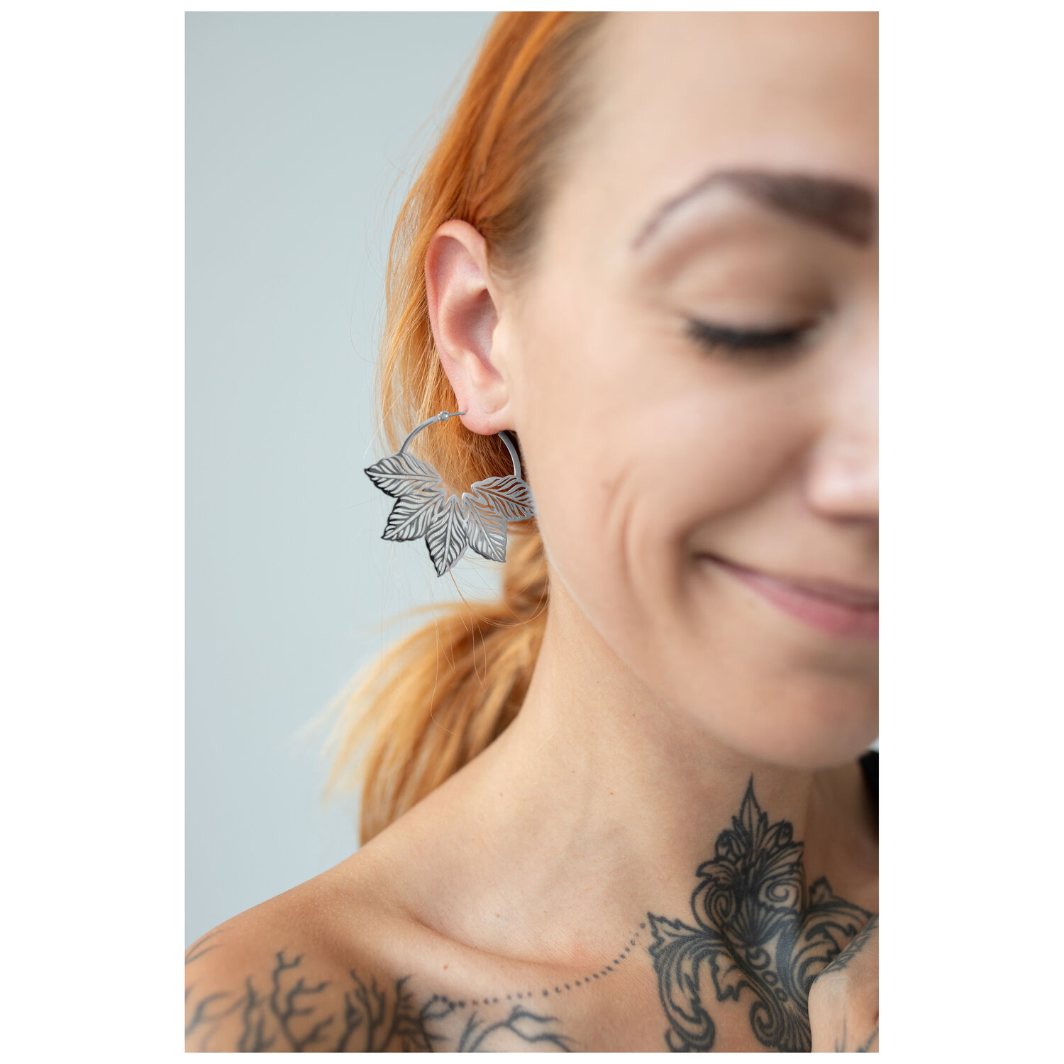 Stylische Abey Hoops en acier inoxydable Gros plan d'une femme portant des boucles d'oreilles Abey Hoops avec un design de feuille élégant