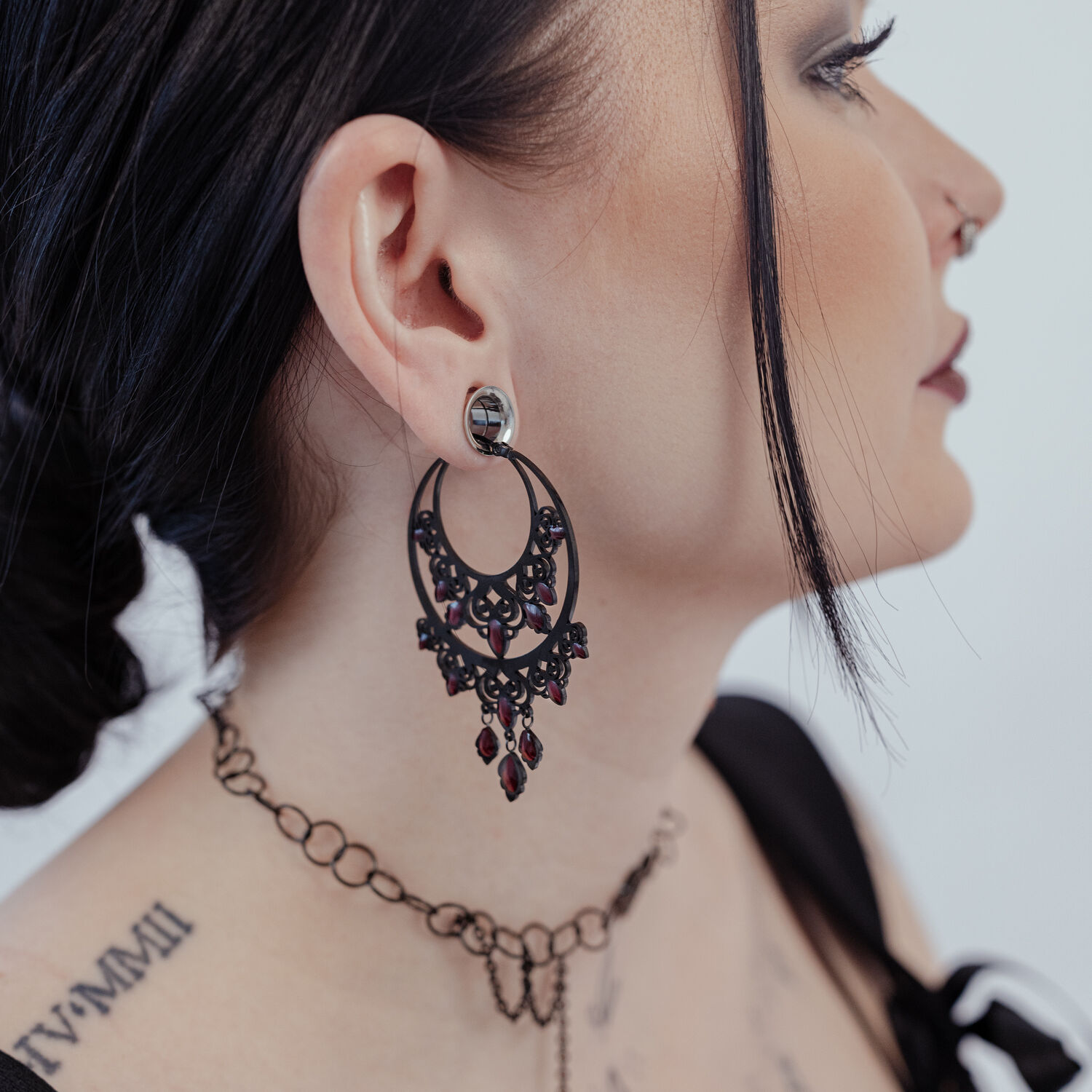 Créoles Chandelier Baroques en Noir Boucles d'oreilles baroques noires en acier chirurgical sur l'oreille d'une femme, profil latéral