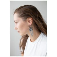 La Fleur Hoops en noir et argent Femme aux longs cheveux portant des boucles d'oreilles La Fleur Hoops noires et argentées