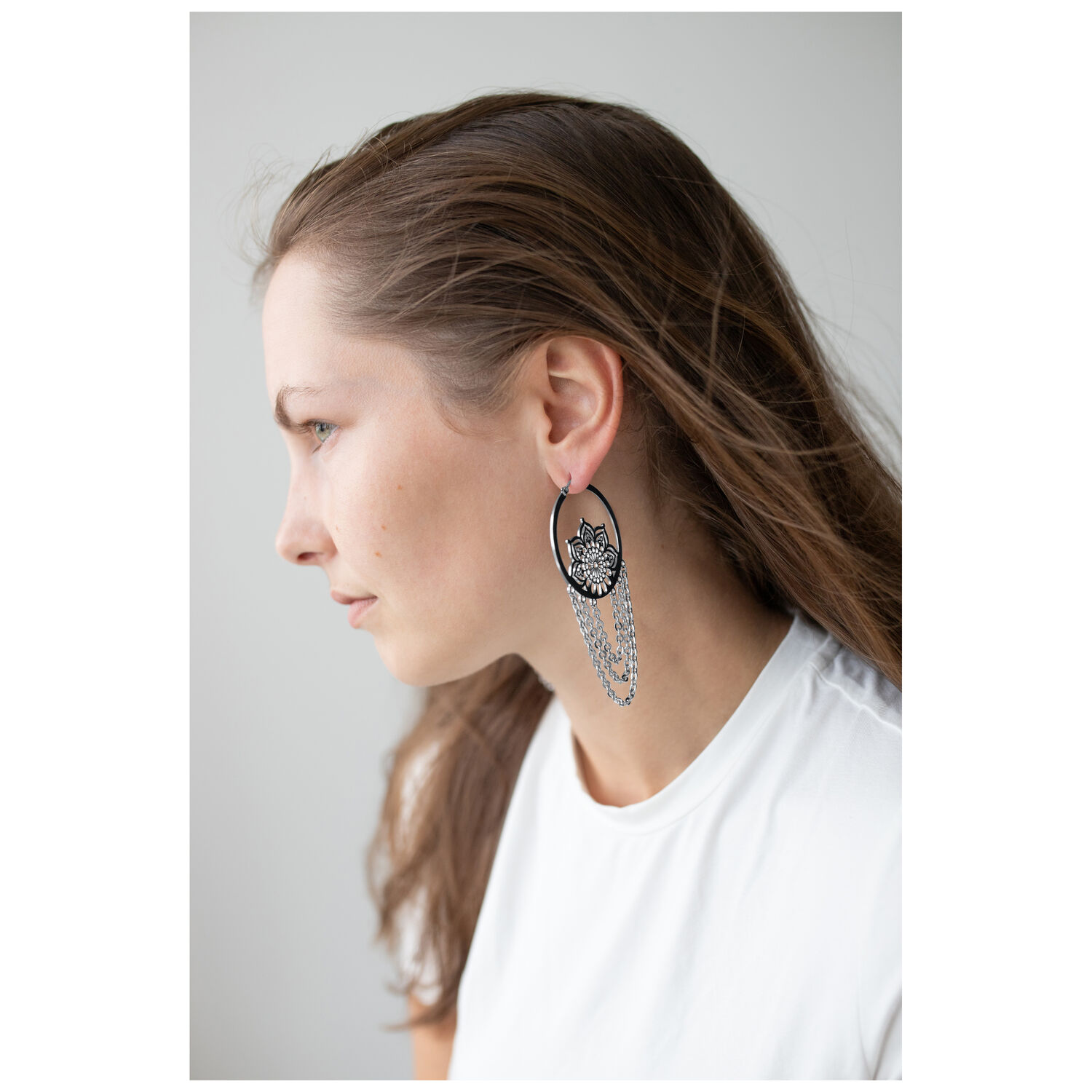 La Fleur Hoops en noir et argent Femme aux longs cheveux portant des boucles d'oreilles La Fleur Hoops noires et argentées