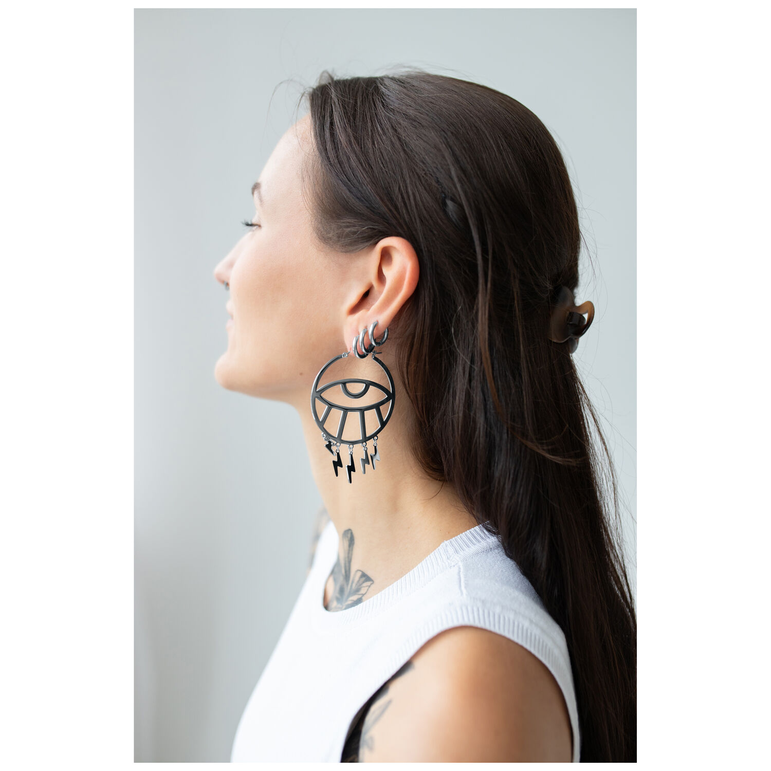 Thunderflash Eye Hoops portés en noir Femme aux longs cheveux portant de grandes boucles d'oreilles Thunderflash Eye Hoops noires de côté