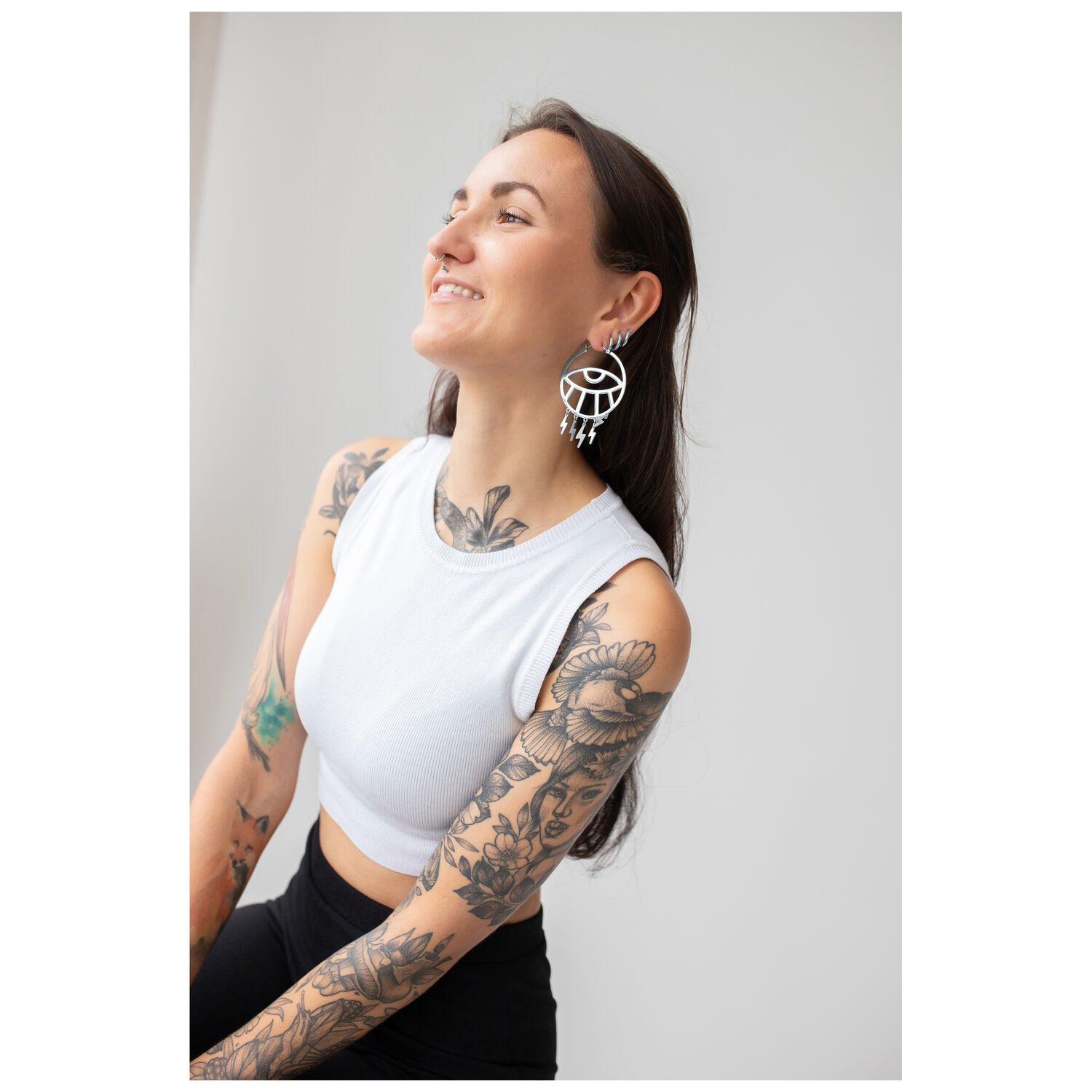 Thunderflash Eye Hoops portés à l'oreille Femme aux longs cheveux portant des Thunderflash Eye Hoops voyants, top blanc