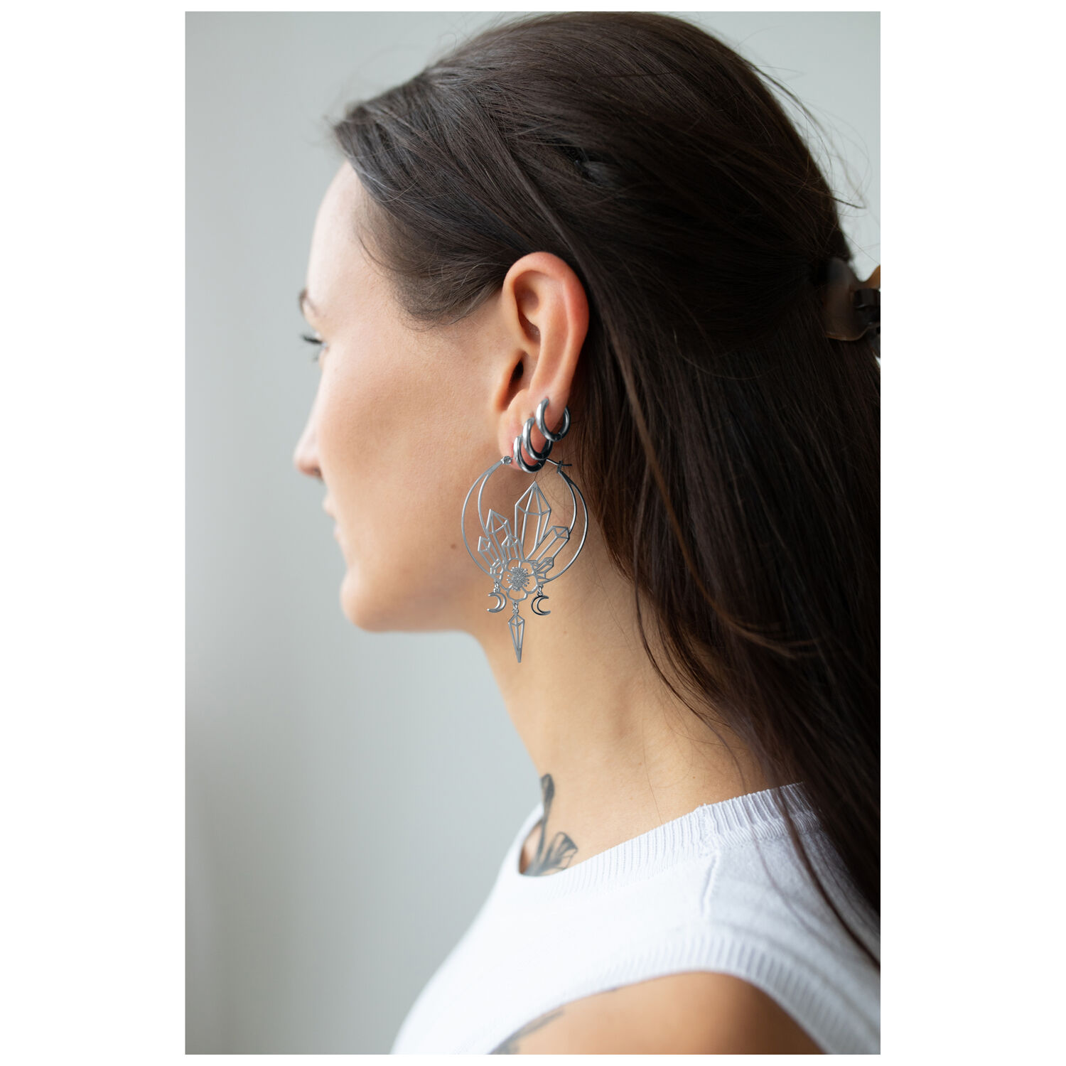 Boucles d'oreilles Oracle Hoops stylées en noir Jeune femme aux longs cheveux portant de grandes boucles d'oreilles Oracle Hoops noires de profil