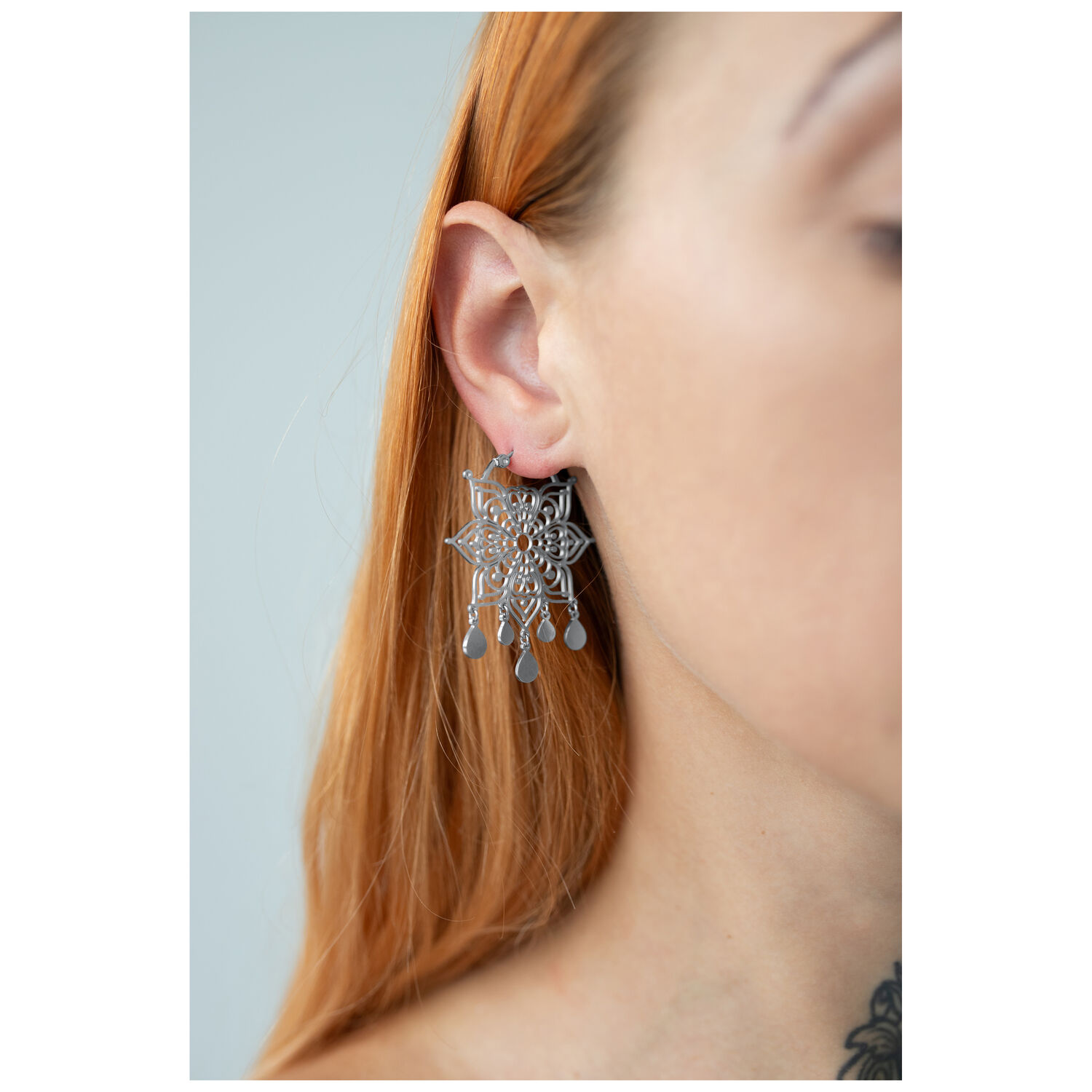 Boucles d'oreilles Mandala argentées portées, focus sur l'oreille, cheveux blonds