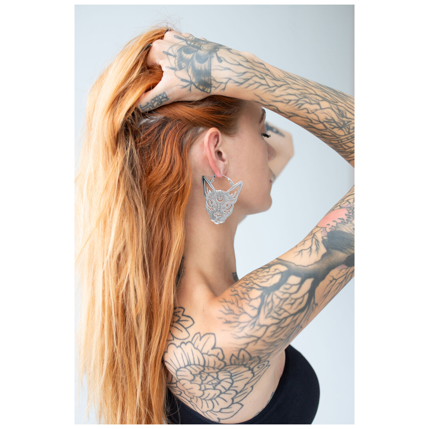 Sphynx Hoops en acier chirurgical argenté Femme aux cheveux roux portant des Sphynx Hoops argentés sur fond clair