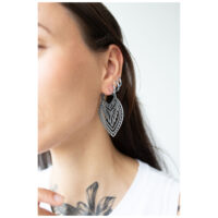 Femme avec des boucles d'oreilles Creek Hoops en argent, portées à l'oreille, fond blanc