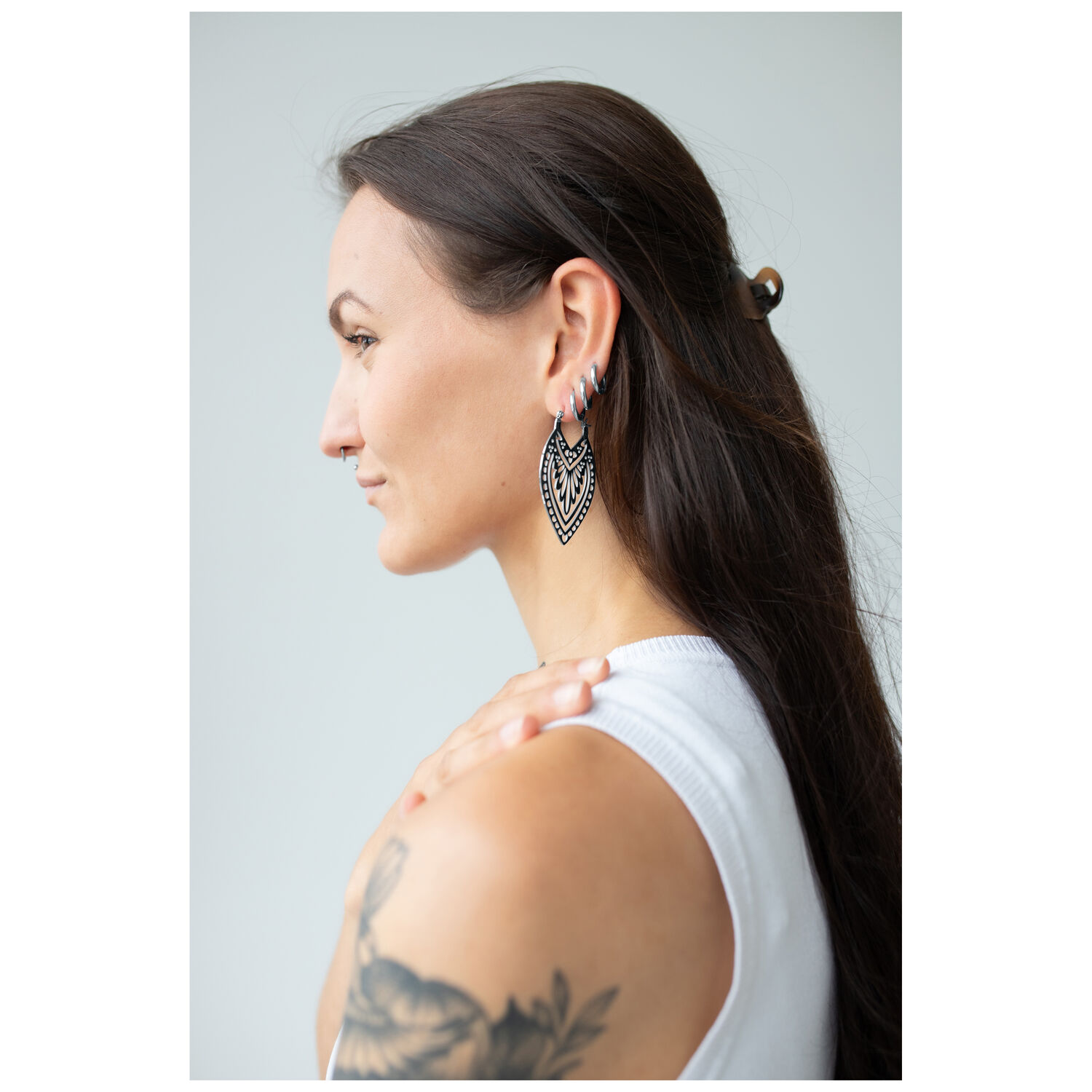 Femme aux longs cheveux portant des boucles d'oreilles Creek Hoops en argent sur fond neutre