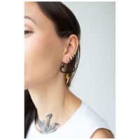 Boucles d'oreilles nuages noirs avec éclair Femme portant des boucles d'oreilles nuages noirs avec éclair doré sur fond clair