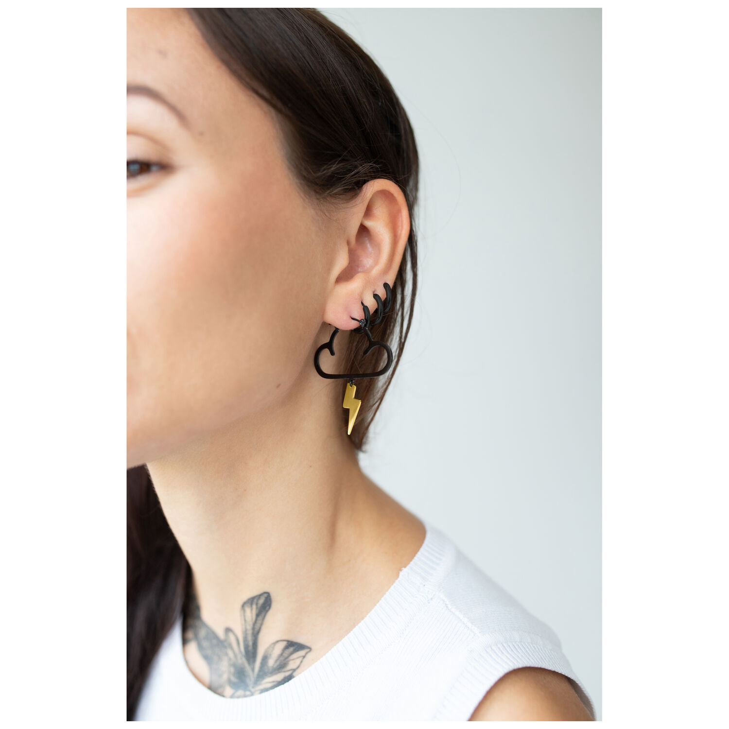 Boucles d'oreilles nuages noirs avec éclair Femme portant des boucles d'oreilles nuages noirs avec éclair doré sur fond clair