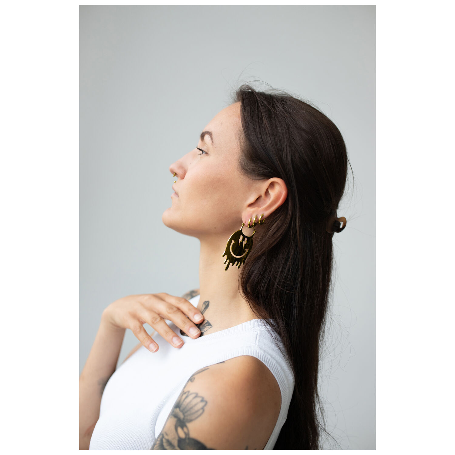 Smiley Big Hoops Paires en Or à l'Oreille Femme aux cheveux longs portant des boucles d'oreilles Smiley en or sur fond gris
