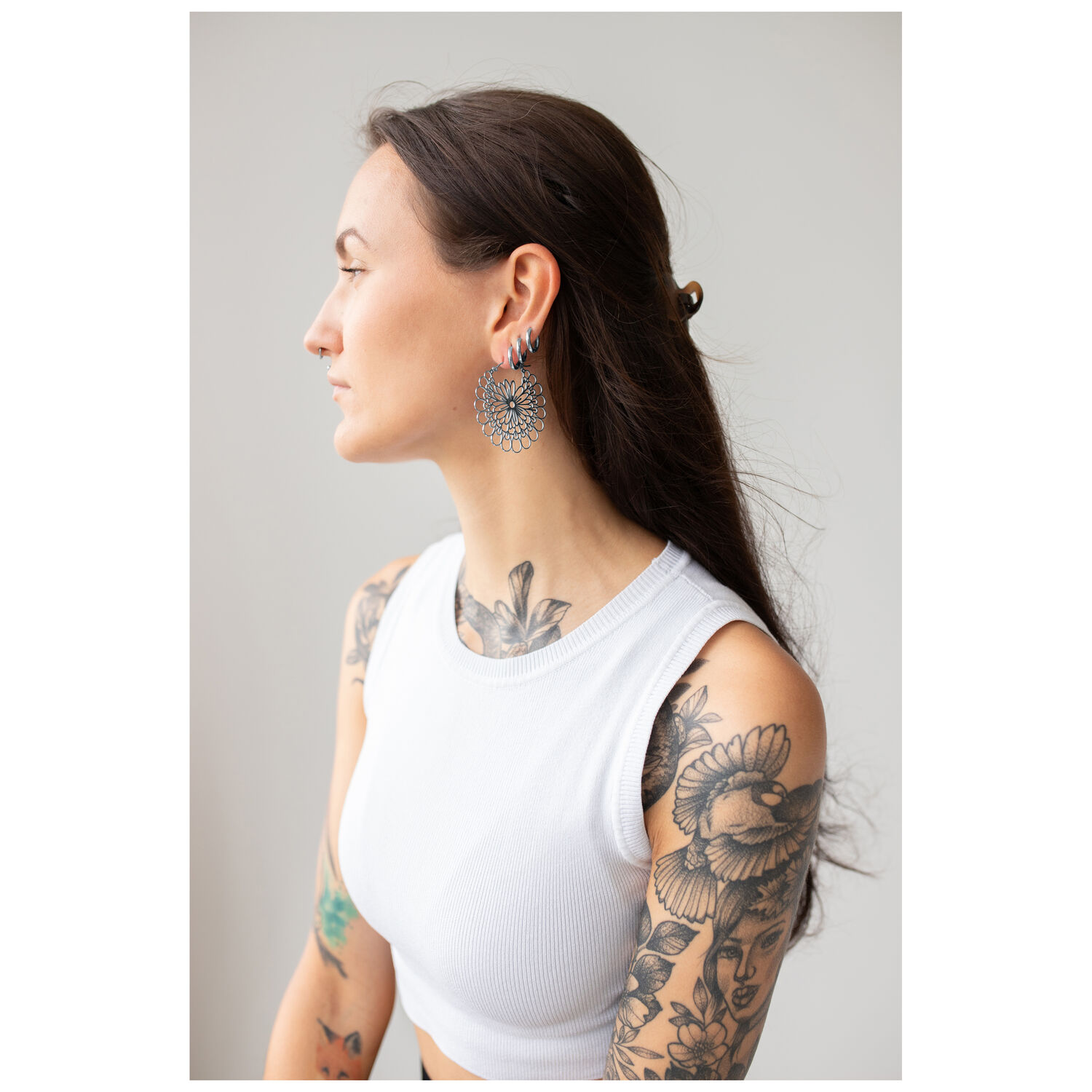 Boucles d'oreilles Daisy Hoops en noir et argent Femme avec des boucles d'oreilles Daisy Hoops en noir et argent sur fond gris