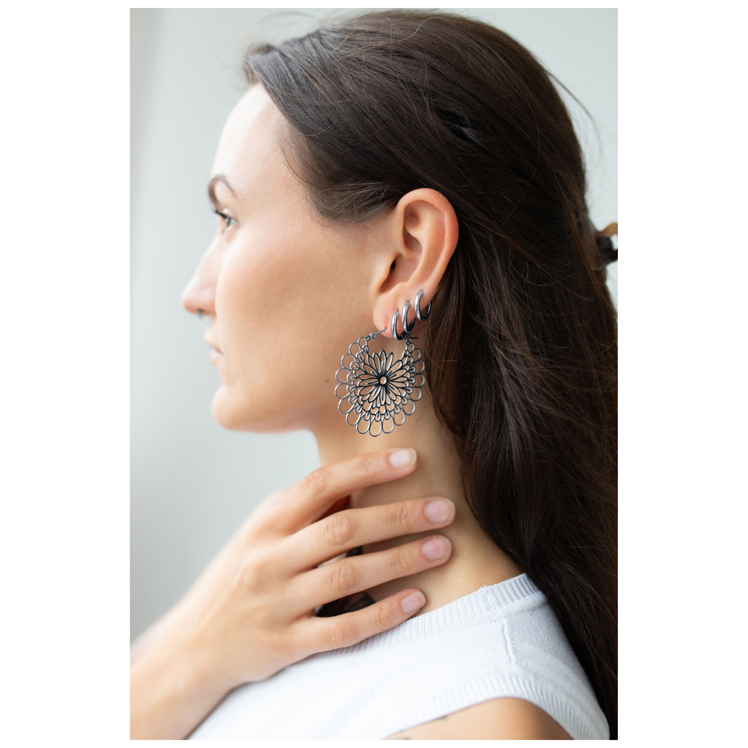 Boucles d'oreilles Daisy Hoops en argent et noir Femme portant des boucles d'oreilles Daisy Hoops en acier chirurgical noir et argent.