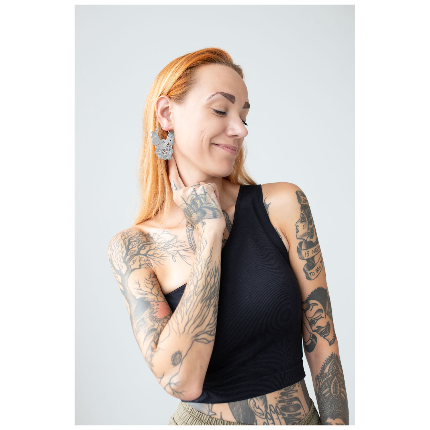 Boucles d'oreilles Bulldog Hoops sur femme tatouée Femme tatouée portant de grandes boucles d'oreilles Bulldog Hoops