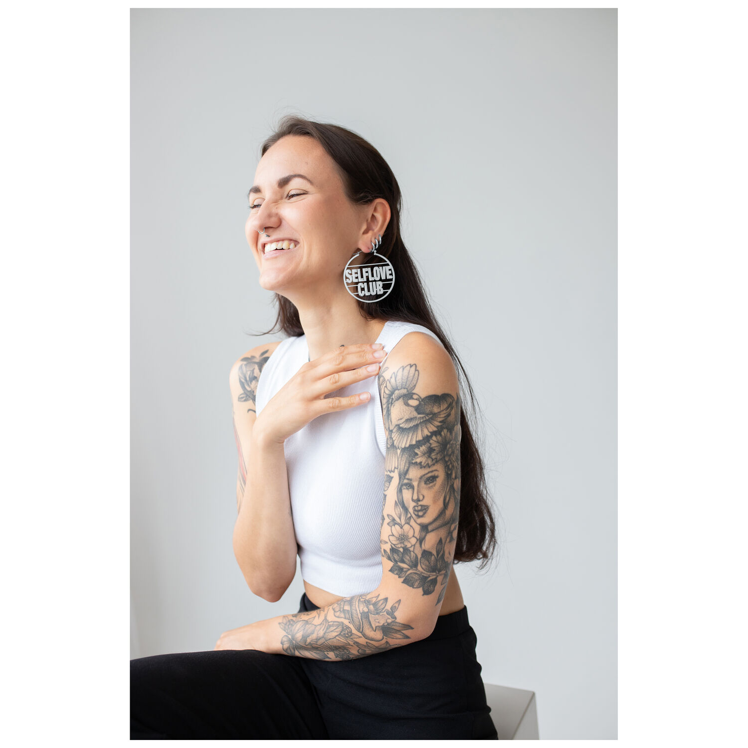 Selflove Club Hoops sur personne souriante Personne souriante aux longs cheveux avec des Selflove Club Hoops dans une pièce lumineuse