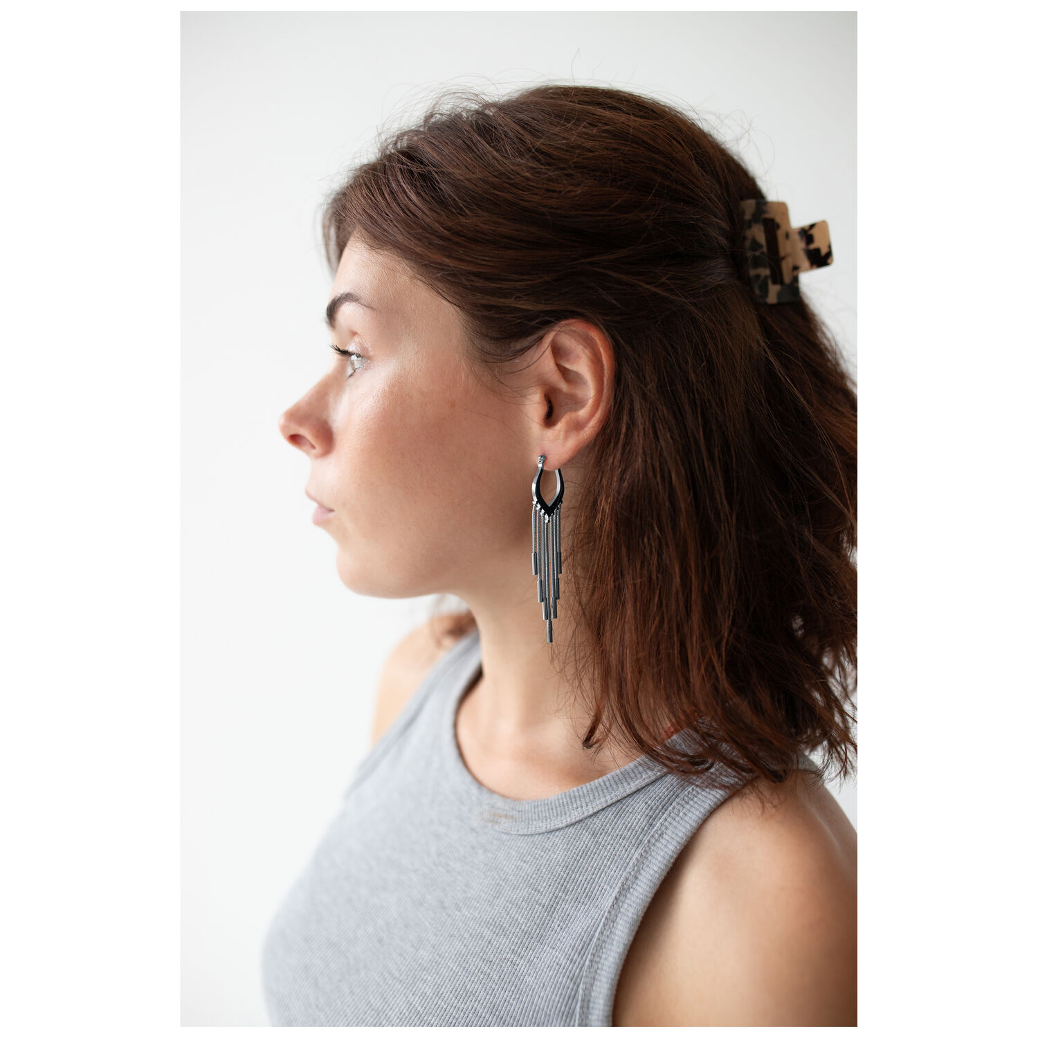 Créoles Snakechain noires portées à l'oreille Femme aux cheveux bruns portant des créoles Snakechain noires sur fond blanc