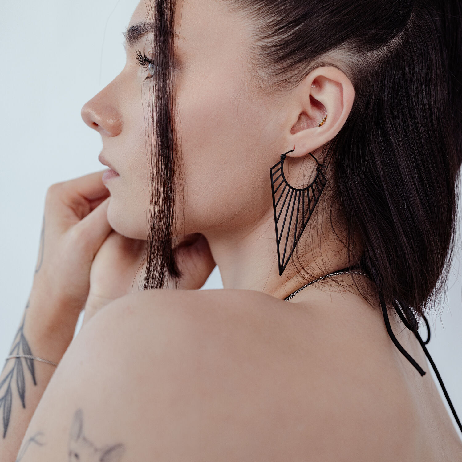 Boucles d'oreilles Prisma Hoops noires sur une femme aux cheveux bruns, photographiée de côté