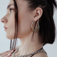 Créoles élégantes avec boucles en argent et or Femme avec des créoles élégantes et massives avec boucles en argent et or sur fond blanc