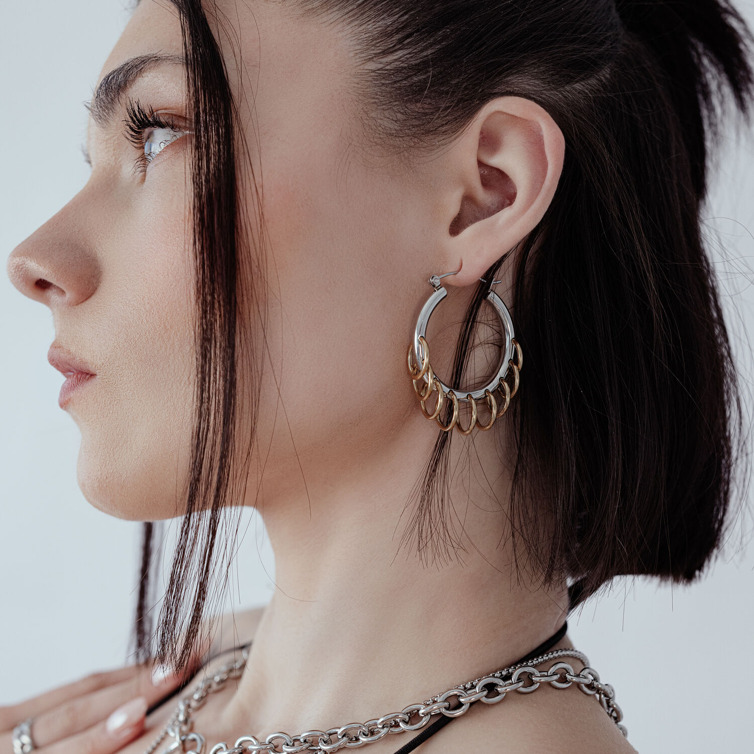 Créoles élégantes avec boucles en argent et or Femme avec des créoles élégantes et massives avec boucles en argent et or sur fond blanc