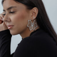 Créoles fleurs en argent à l'oreille d'une femme Créoles fleurs en argent à l'oreille d'une femme aux cheveux foncés, profil latéral sur fond neutre