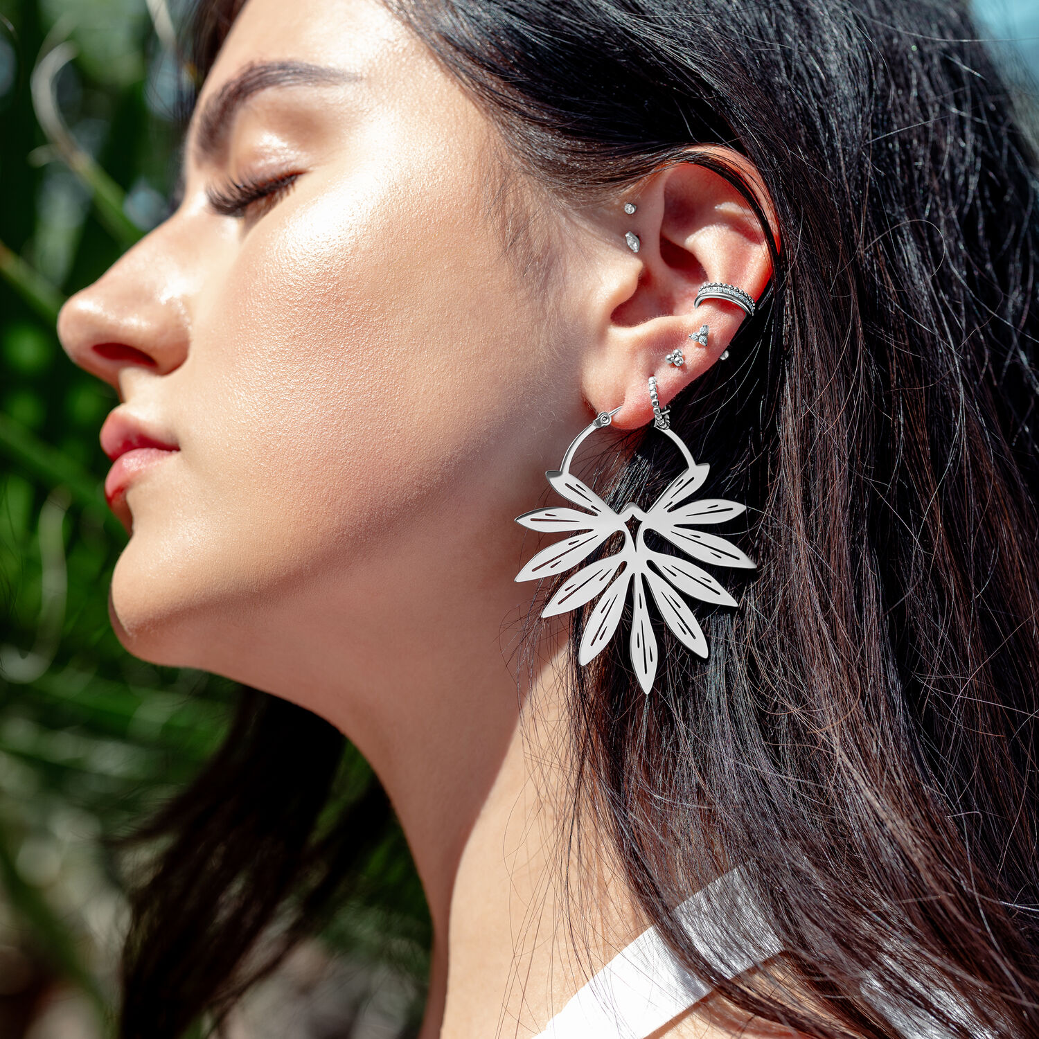 Boucles d'oreilles en bambou élégantes en argent Gros plan d'une femme avec des boucles d'oreilles en bambou argentées au soleil