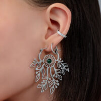 Gros plan d'une oreille avec une boucle d'oreille argentée en forme de fleur et un petit clou