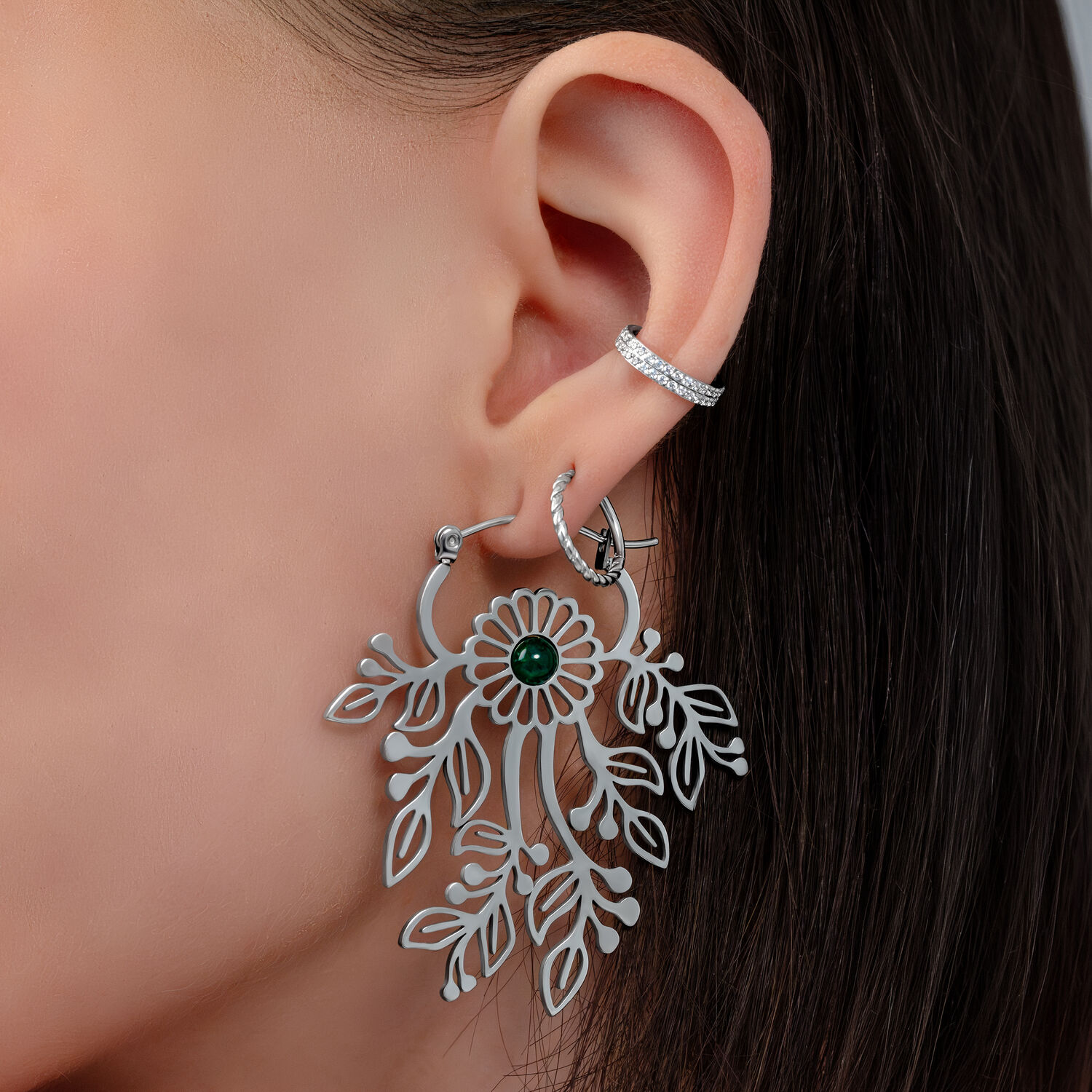 Gros plan d'une oreille avec une boucle d'oreille argentée en forme de fleur et un petit clou