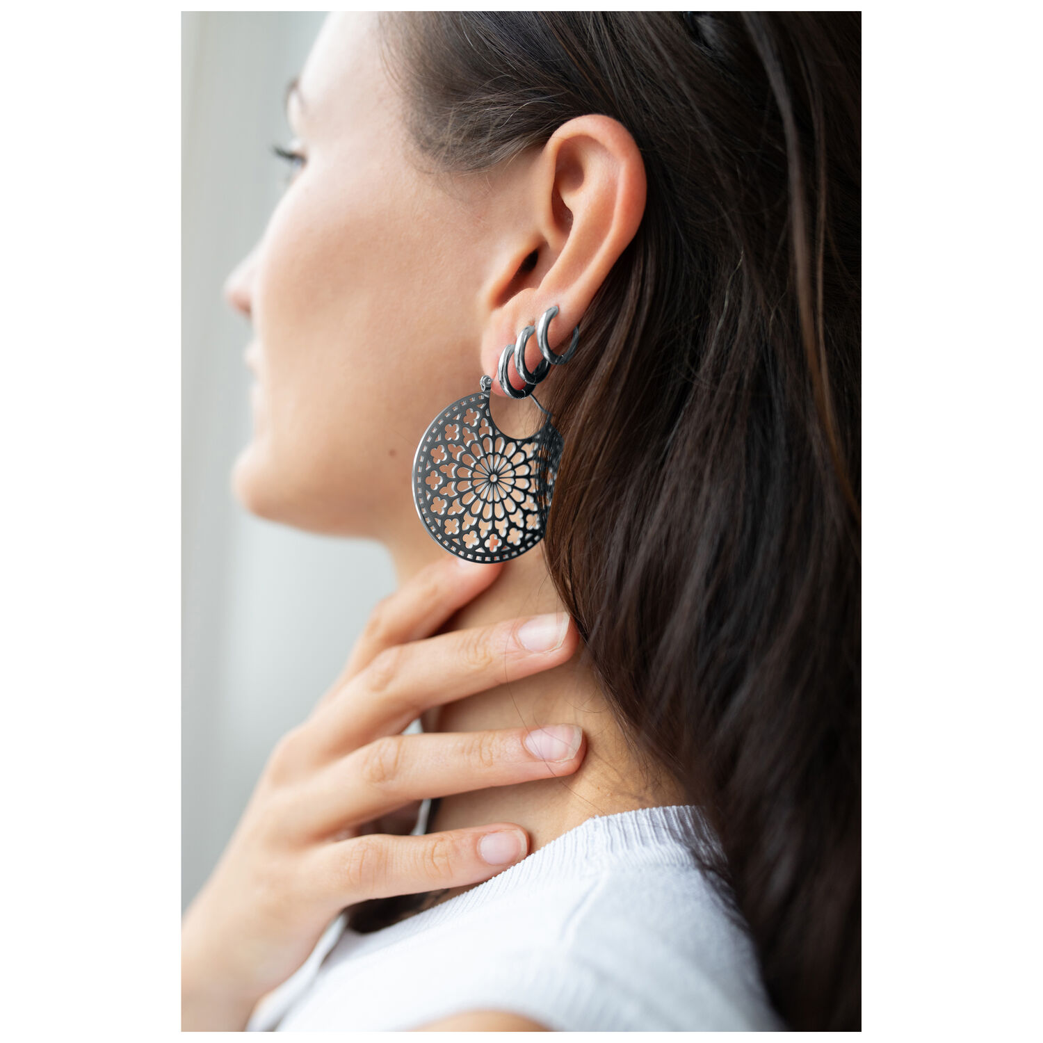Boucles d'oreilles Cathedral Hoops en noir et argent Femme portant de grandes boucles d'oreilles rondes en noir et argent avec un design délicat.