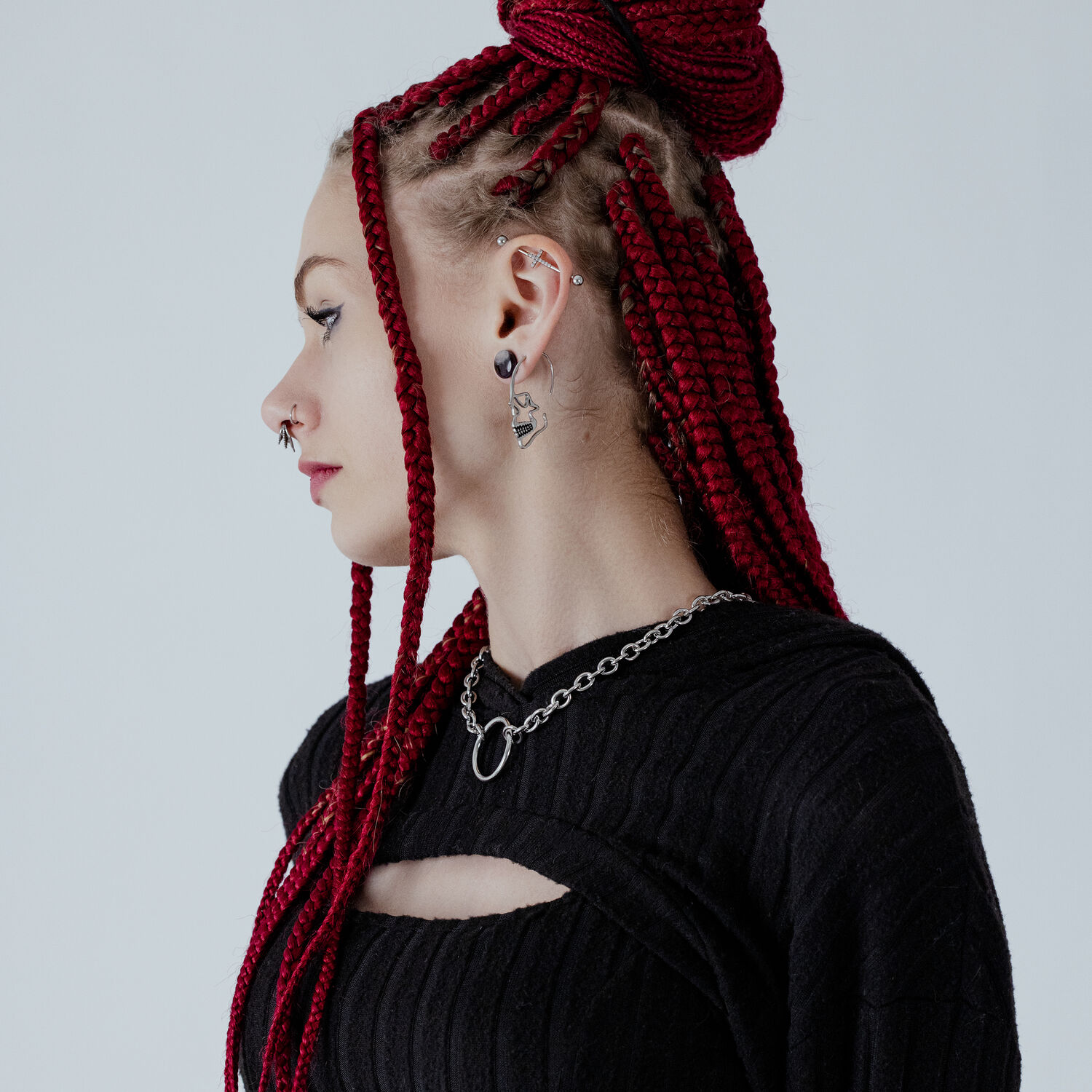 Clou d'oreille crâne argenté de Wildcat Femme avec une tresse rouge portant un clou d'oreille crâne argenté sur fond clair
