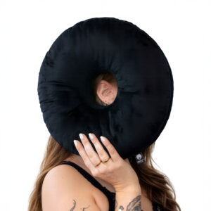 Coussin rond noir en polyester avec ouverture pour l'oreille, tenu par une personne, sur fond blanc