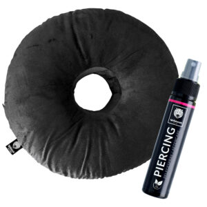 Coussin rond noir pour piercing en polyester avec trou central, à côté un flacon de spray de soin pour piercing sur fond blanc