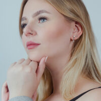 Clicker à double rangée en argent pour oreille et nez Femme portant un clicker à double rangée en argent à l'oreille et un anneau de nez, fond neutre