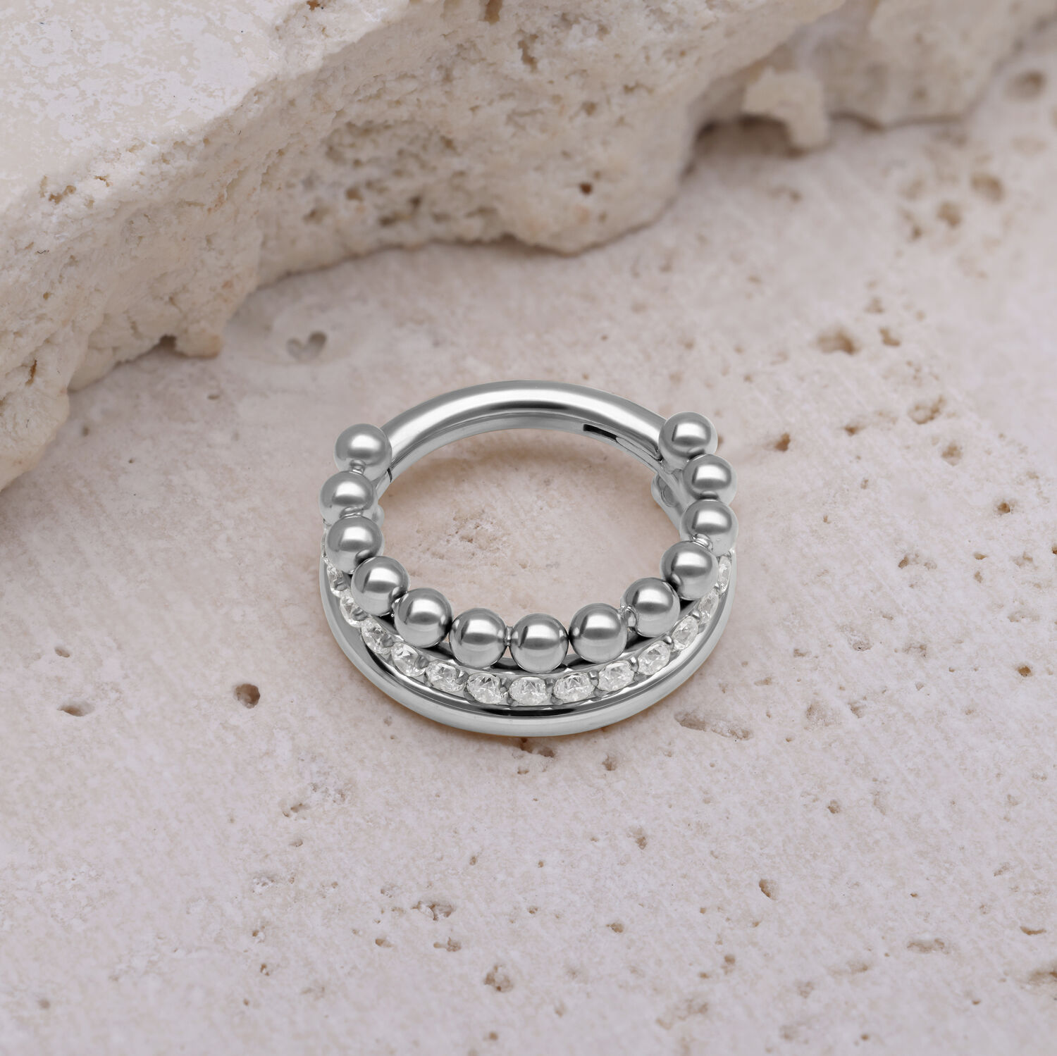 Triple Bubble Clicker en argent avec des cristaux blancs sur une pierre beige