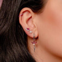 Boucle d'oreille en argent avec cristaux rouges Boucle d'oreille en argent avec cristaux rouges et plusieurs piercings dans une oreille