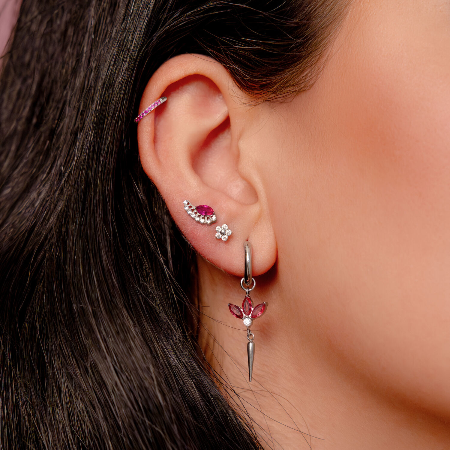Boucle d'oreille en argent avec cristaux rouges Boucle d'oreille en argent avec cristaux rouges et plusieurs piercings dans une oreille