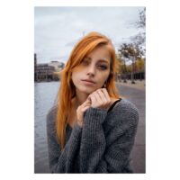 Charmant Clicker en Cristal Pavé Noir Jeune femme avec piercing au nez et pull gris devant un décor urbain