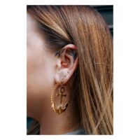 Trinity oreille barbell en or avec ancre Piercings d'oreille en or avec ancre et chaîne, portés à l'oreille d'une femme.
