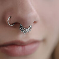Gros plan sur un Triple Oriental Clicker en argent dans le septum d'un visage